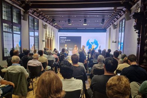 An audience watching a panel discussion in a historic conference hall.