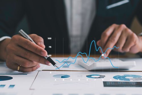 A person reviewing printed charts and graphs with overlaid digital data visuals.