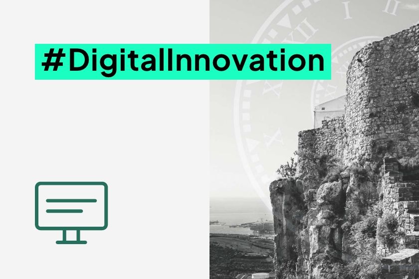 A black and white photo of an ancient stone fortress wall on a hill overlooking the coastline, next to the hashtag #DigitalInnovation.