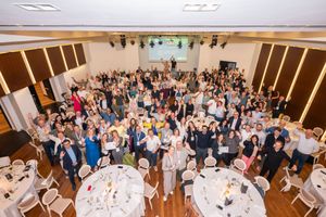 big group of people in a conference room photographed from above, they have their hands in the air