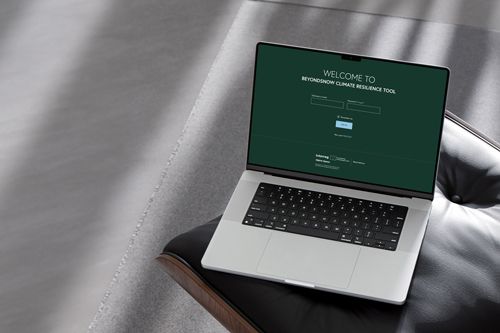 A laptop on a chair displaying the BeyondSnow Climate Resilience Tool login screen.